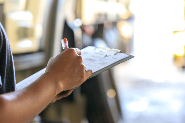 Mechanic holding clipboard with checking truck in service center.