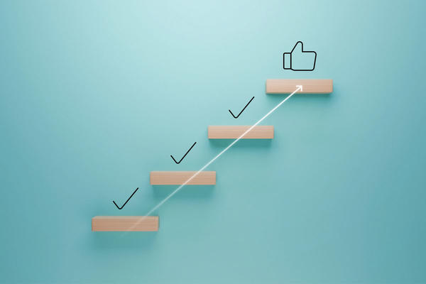 Wooden steps with check marks leading to a thumbs up icon