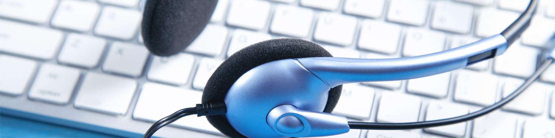 Customer service headset and computer keyboard on the blue background.