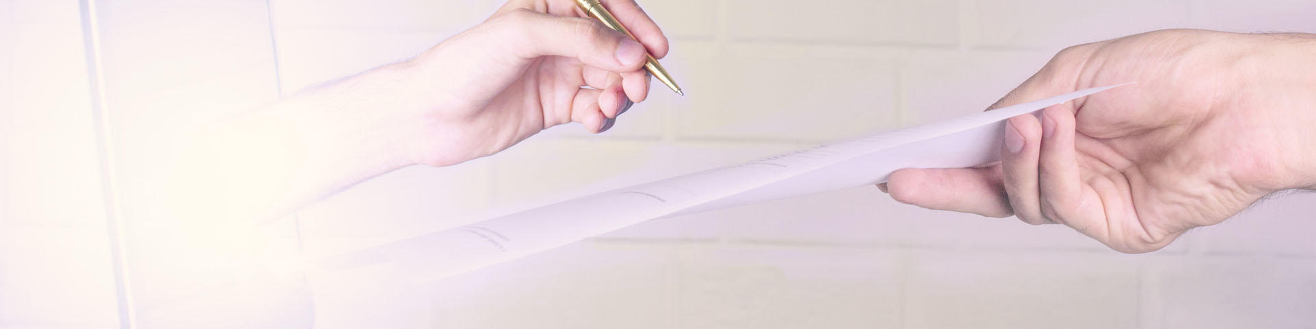 Open laptop, hand holding a pen and paper