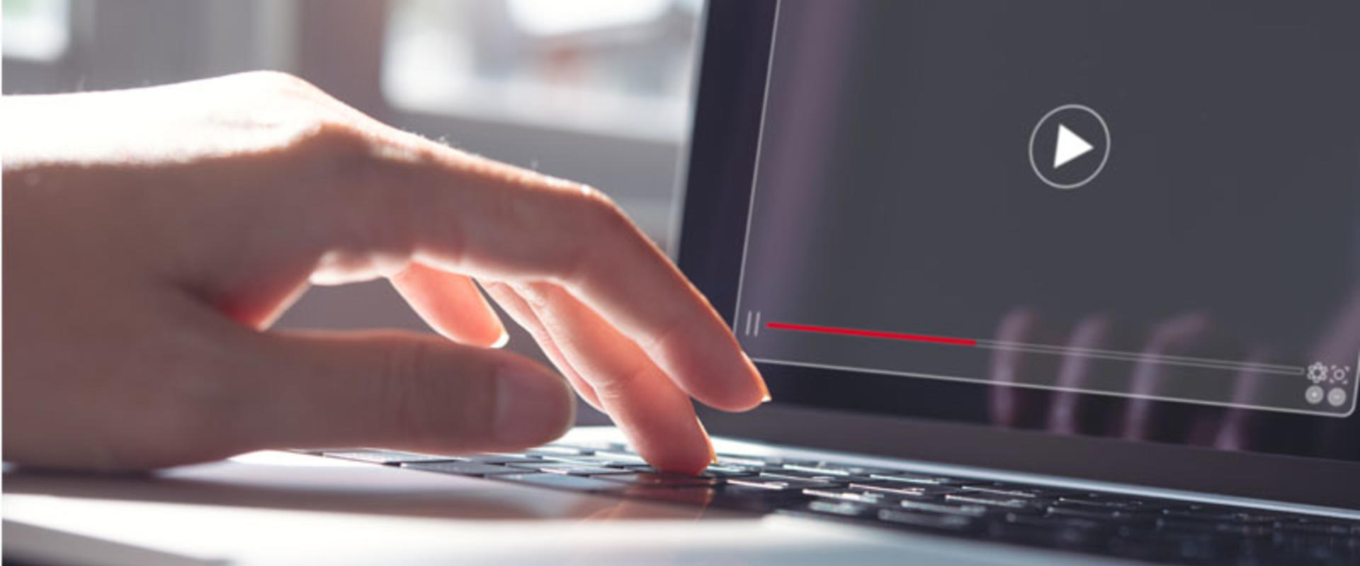 Woman working on laptop computer watching video player